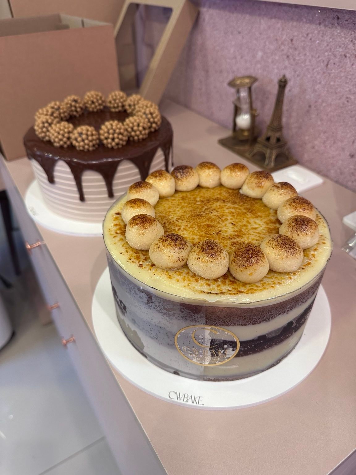 Dois bolos: um com drip de chocolate e brigadeiros e outro naked com brigadeiros de brulée