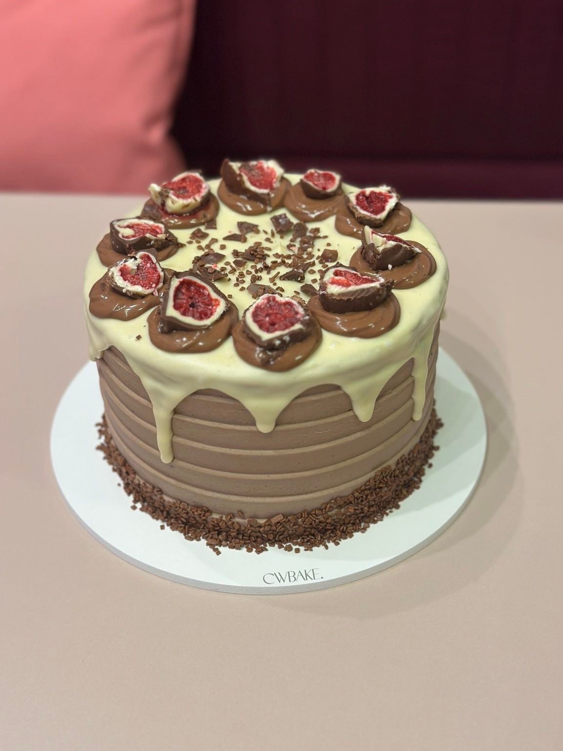 Bolo com drip de chocolate branco, rosetas de chocolate e framboesas no topo