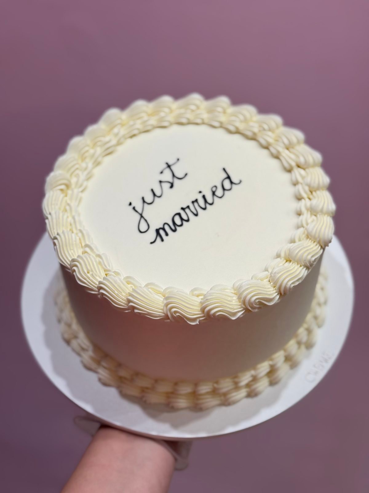 Bolo com a frase “just married” escrita no topo e borda em buttercream