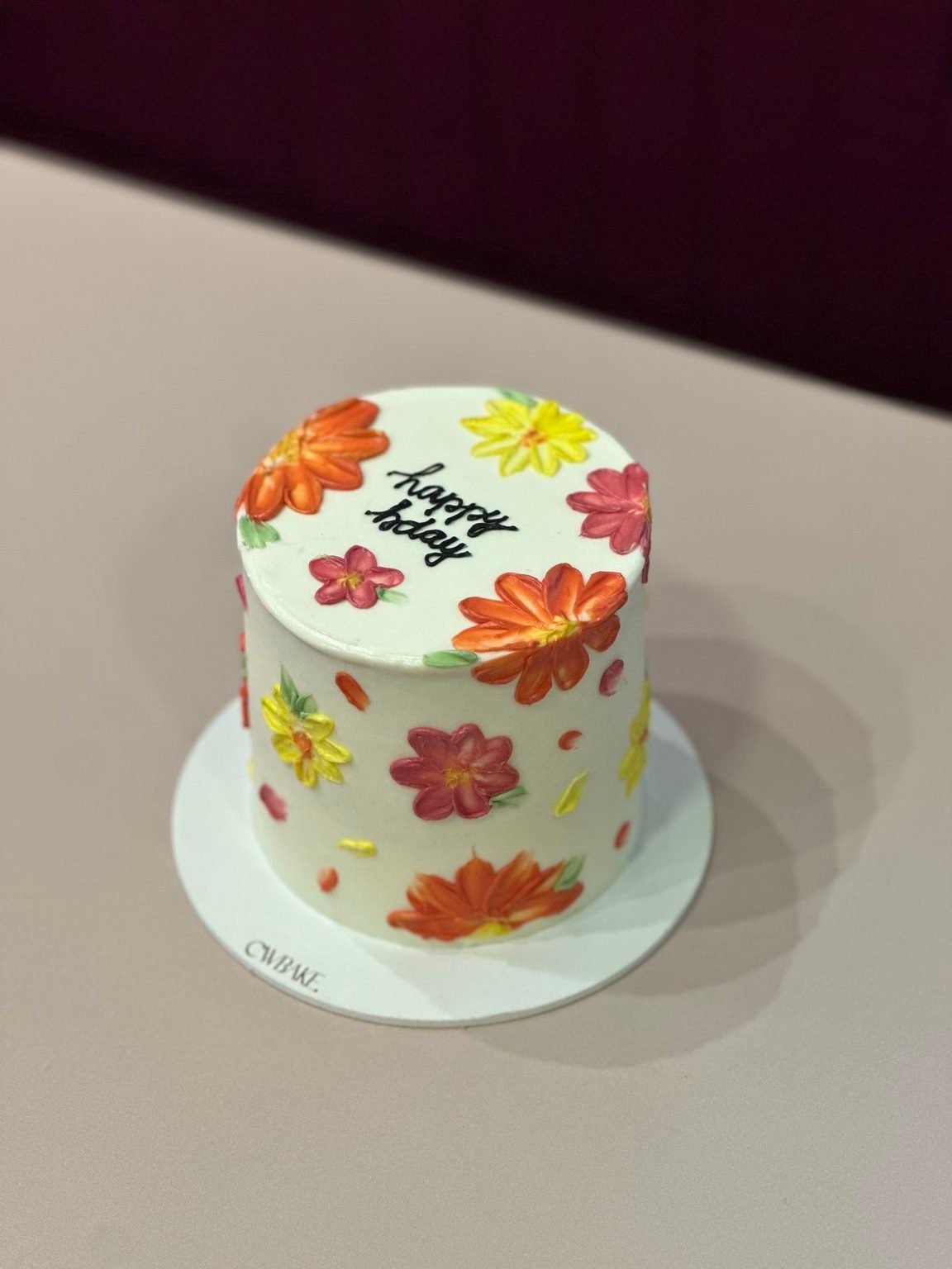 Bolo alto branco com flores laranja e amarelas pintadas à mão