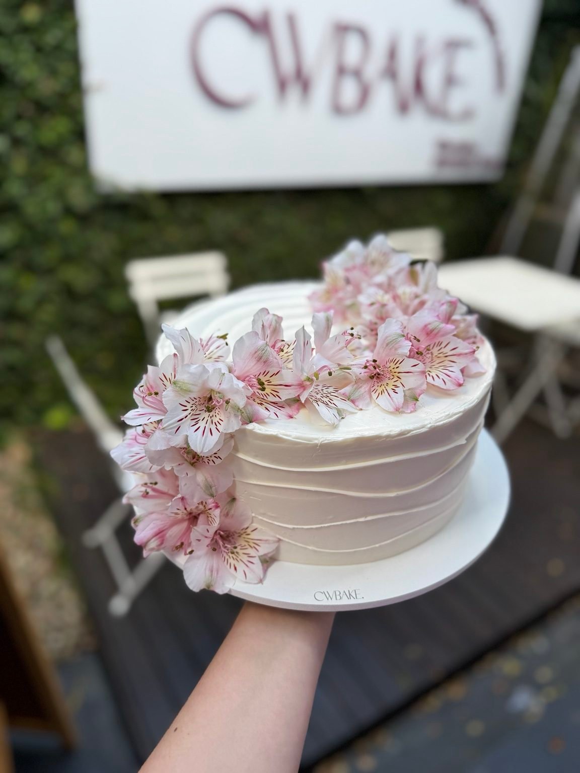 Bolo branco com flores naturais rosadas na lateral