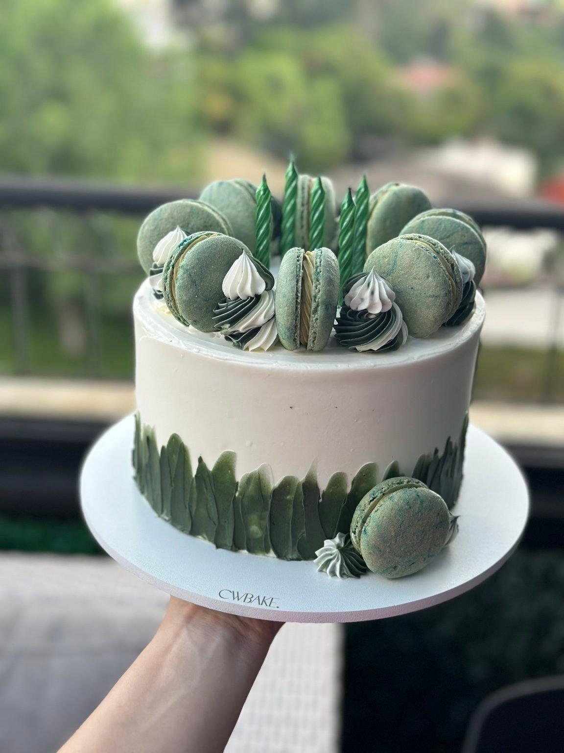 Bolo branco com textura verde e macarons verdes no topo