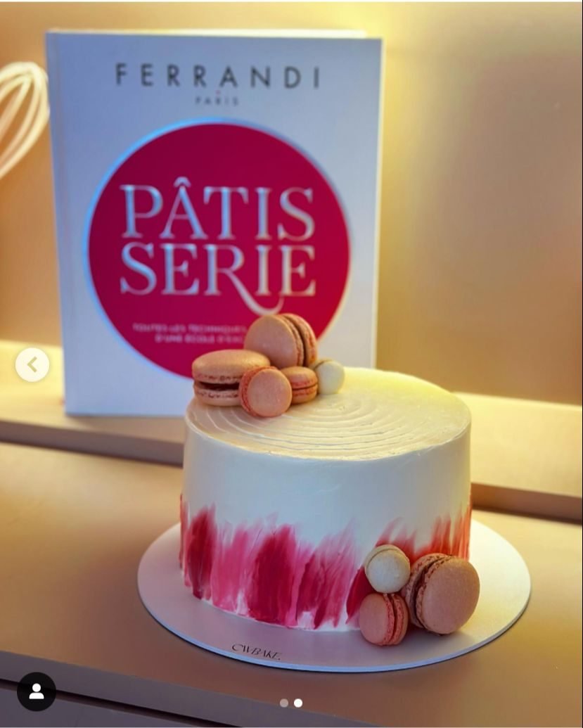 Bolo branco com pinceladas cor-de-rosa e macarons no topo e na base