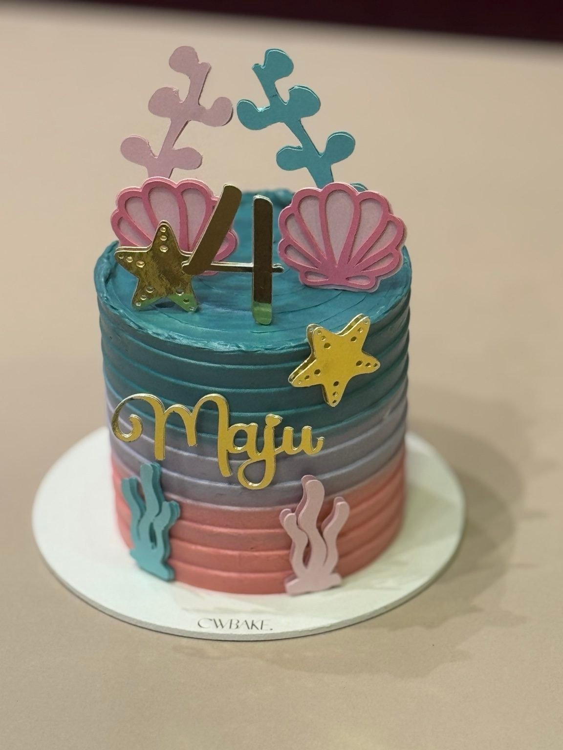Bolo com papelaria de tema sereia, conchas, estrelas-do-mar e nome