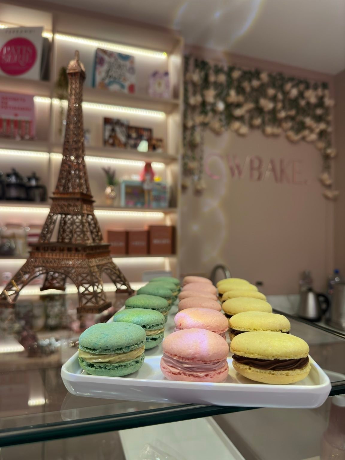 Macarons coloridos em bandeja, ao lado de uma Torre Eiffel decorativa